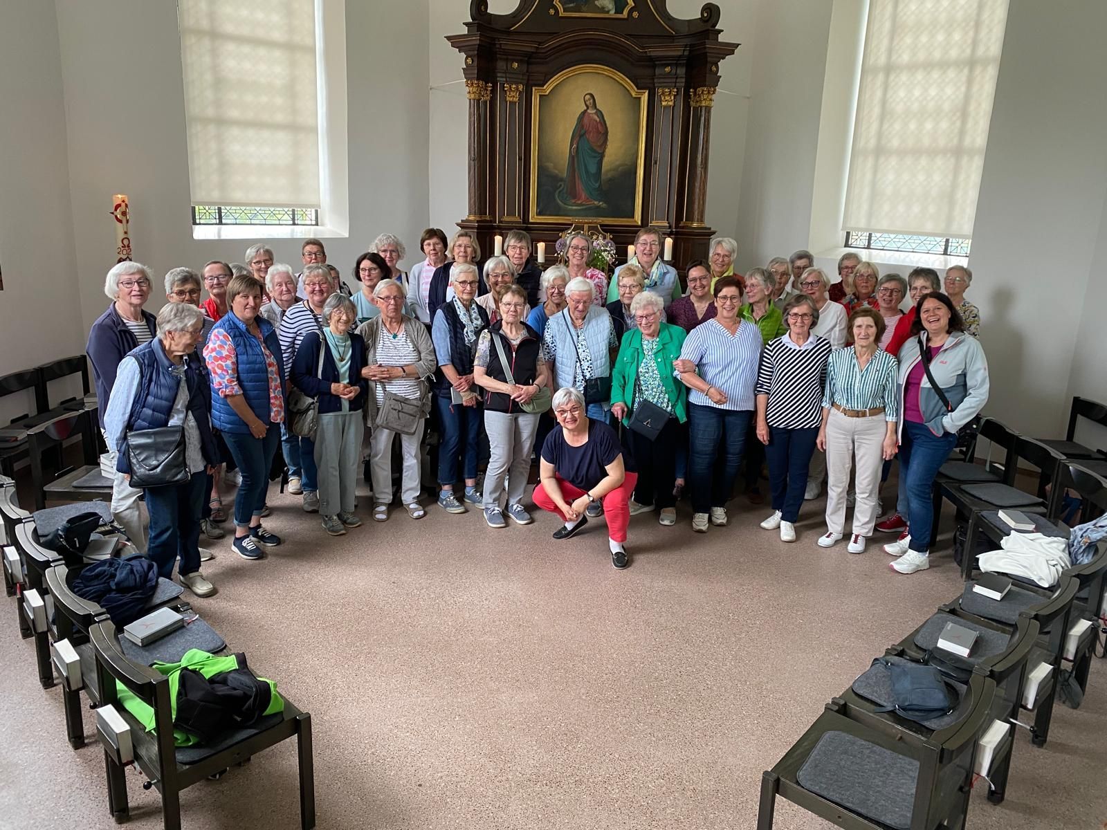 Eine große Gruppe von Menschen posiert in einer Kirche für ein Foto.