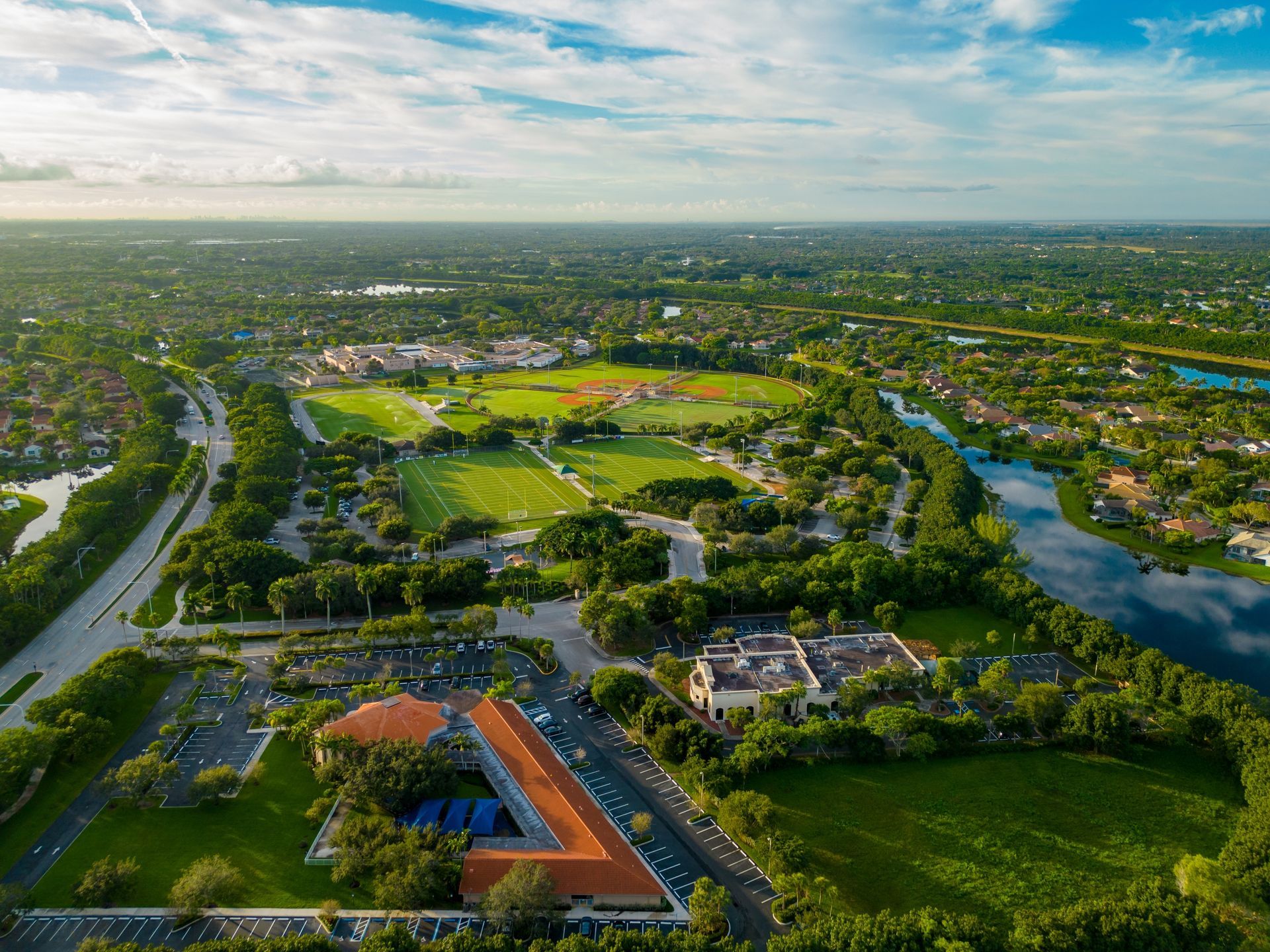 An aerial view of a park surrounded by trees and a river.