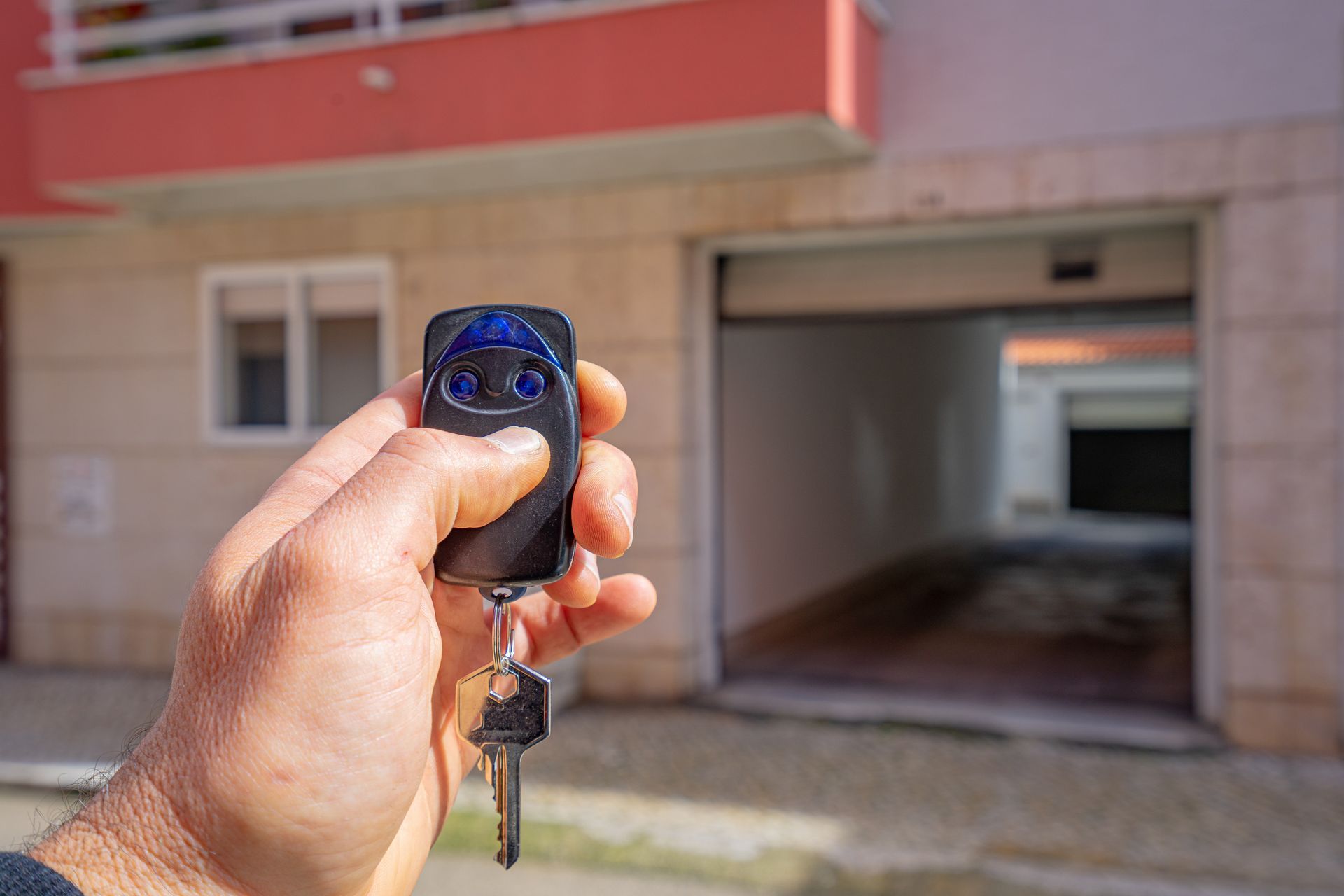 Person using a remote control to open a home garage door from the driveway