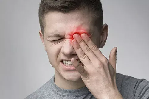 Man in pain with his left hand on his left eye