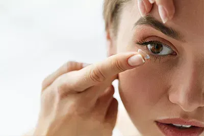 Lady putting on a contact lens with her right index finger