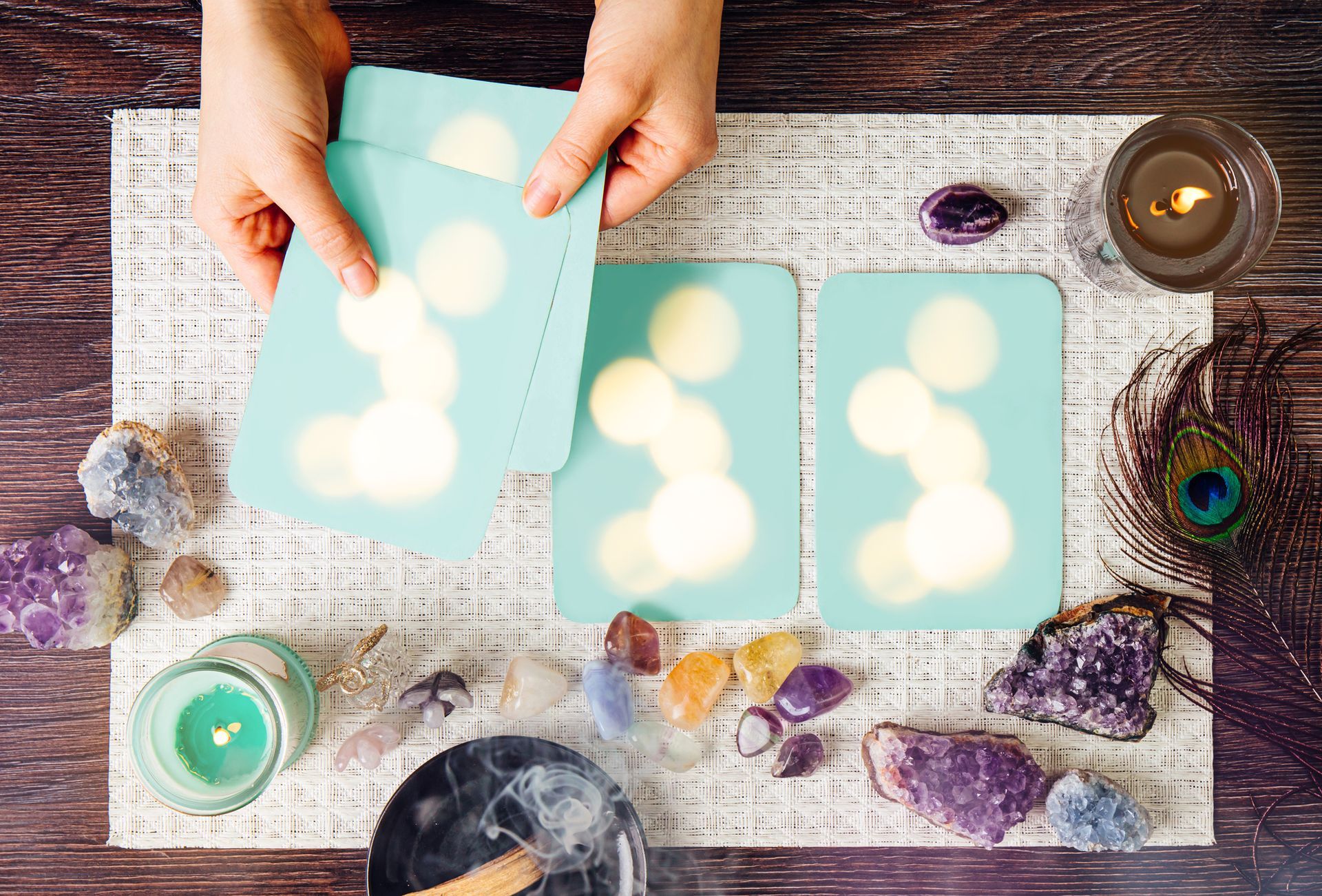 A tarot deck used for psychic readings, surrounded by semi-precious stones, crystals, and candles.