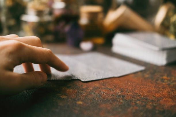Hand selecting a card from a deck on a rustic table with blurred background.