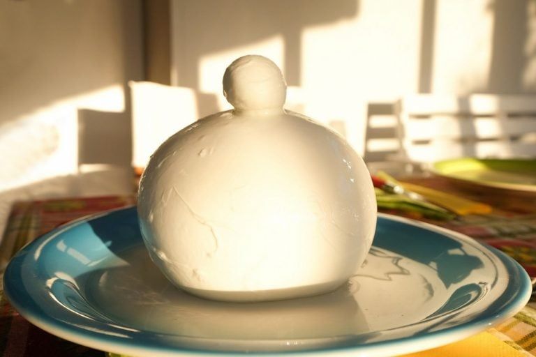 Un uomo sorride con un vassoio di pasticcini davanti a un murale di Napoli, Italia.