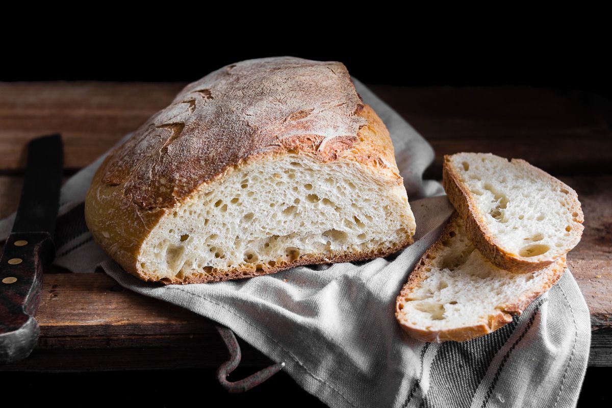 Pagnotta rotonda di Pane Cafone su un tovagliolo di lino, appoggiata su una superficie di legno.