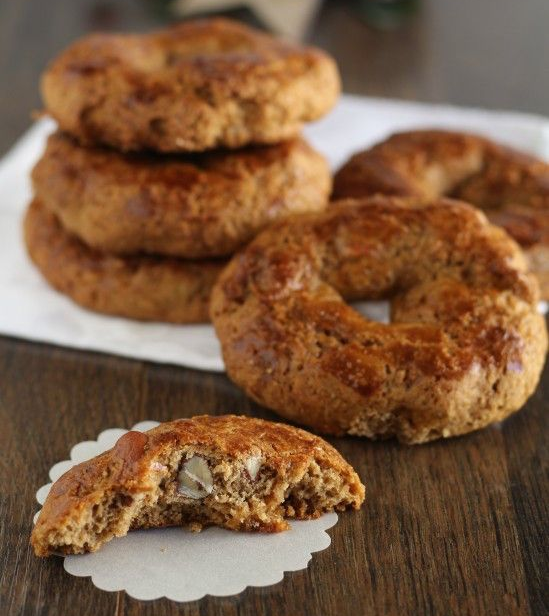 Pila di sei biscotti marroni, spolverati con zucchero a velo, su un piatto di legno, con altri biscotti in una ciotola di legno.