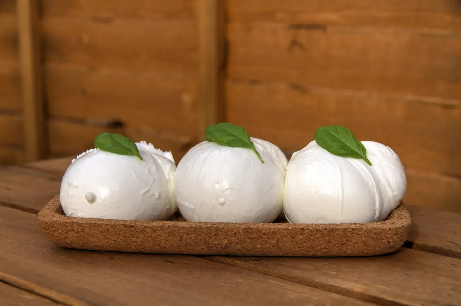 Una palla di mozzarella bianca su un piatto bianco, con uno sfondo di legno.