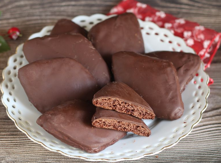 Biscotti a forma di diamante ricoperti di cioccolato, disposti su un piatto beige.