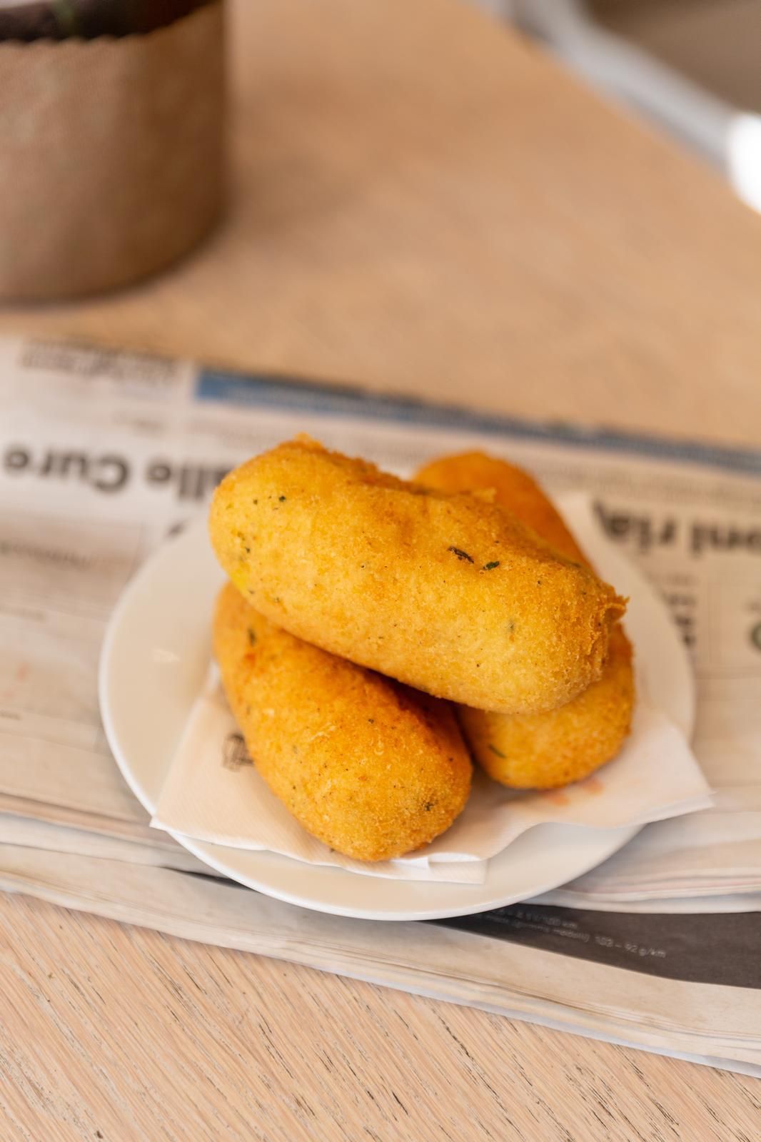 Crocchette di patate fritte dorate, una delle quali tagliata a metà per rivelare il formaggio fuso, su un piatto.