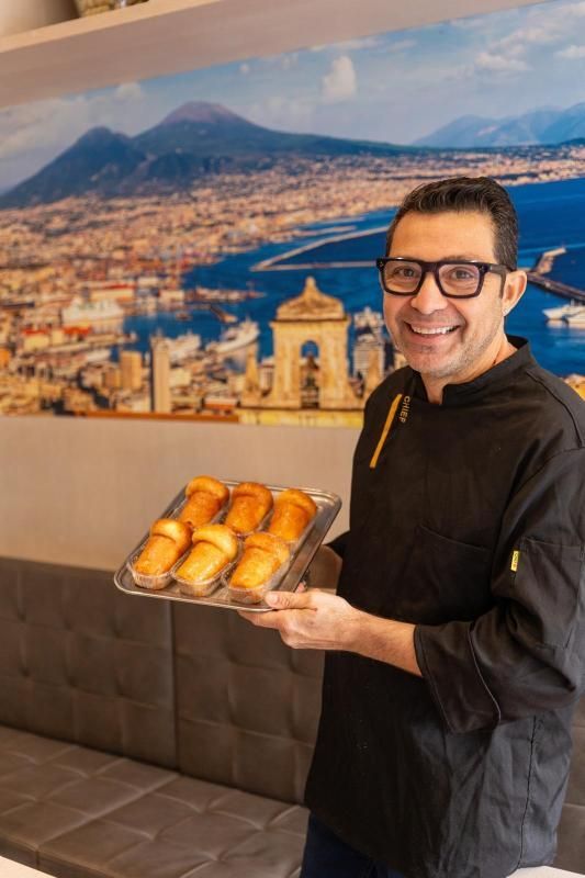 Babà al rhum con panna montata su un piatto bianco, appoggiato su una superficie di legno.