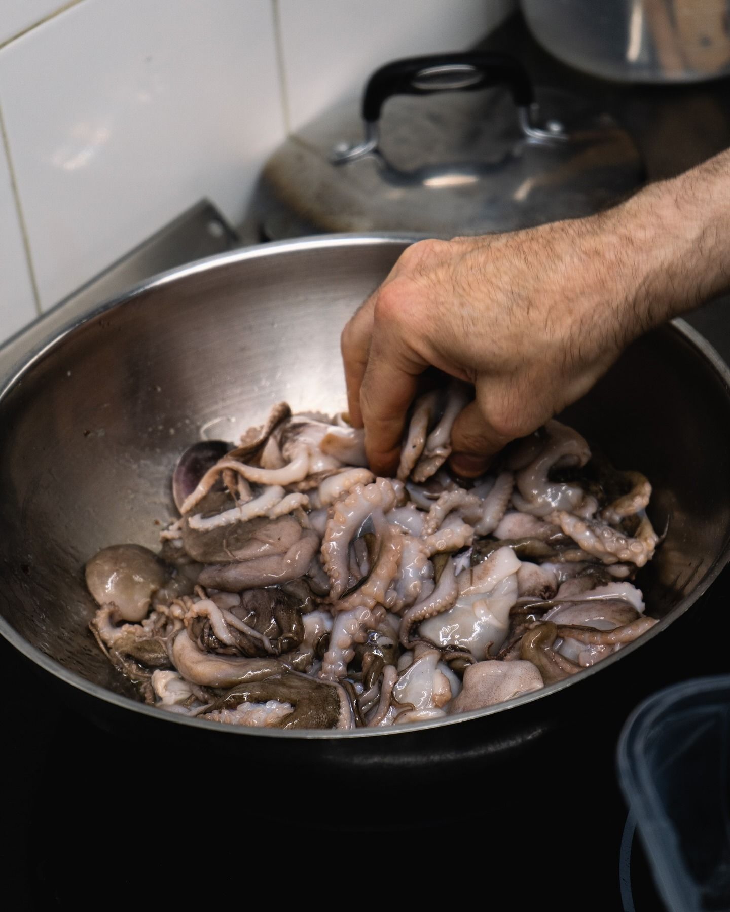 Uomo che tiene in mano una scatola bianca, in piedi fuori da un ristorante con la tavola apparecchiata, giornata di sole.
