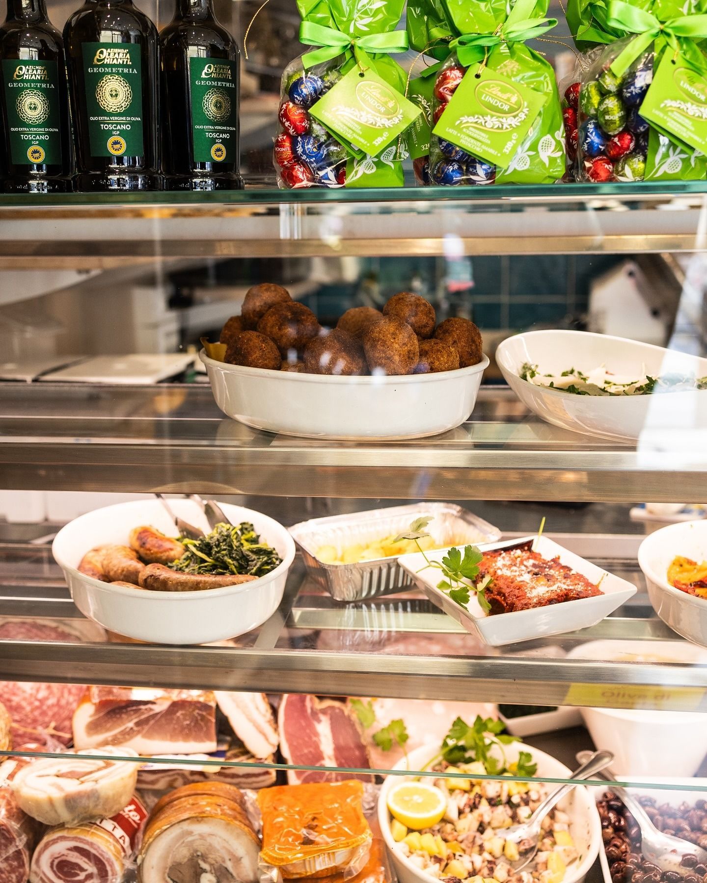 Vetrina espositiva con vari piatti, tra cui polpette, verdure e carne.