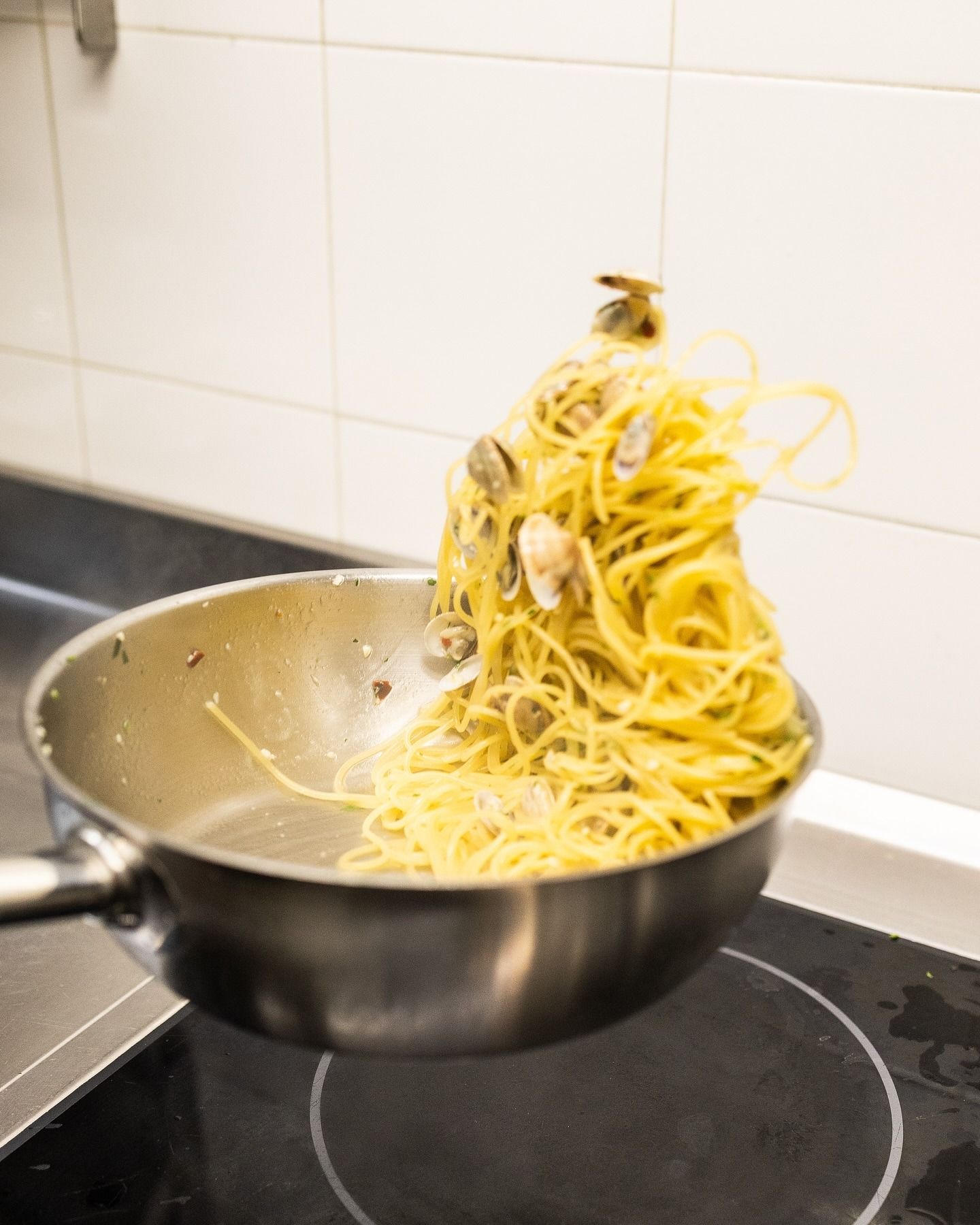 Mano che versa vino rosso in un bicchiere da un rubinetto in un bar, sfondo di piastrelle blu.