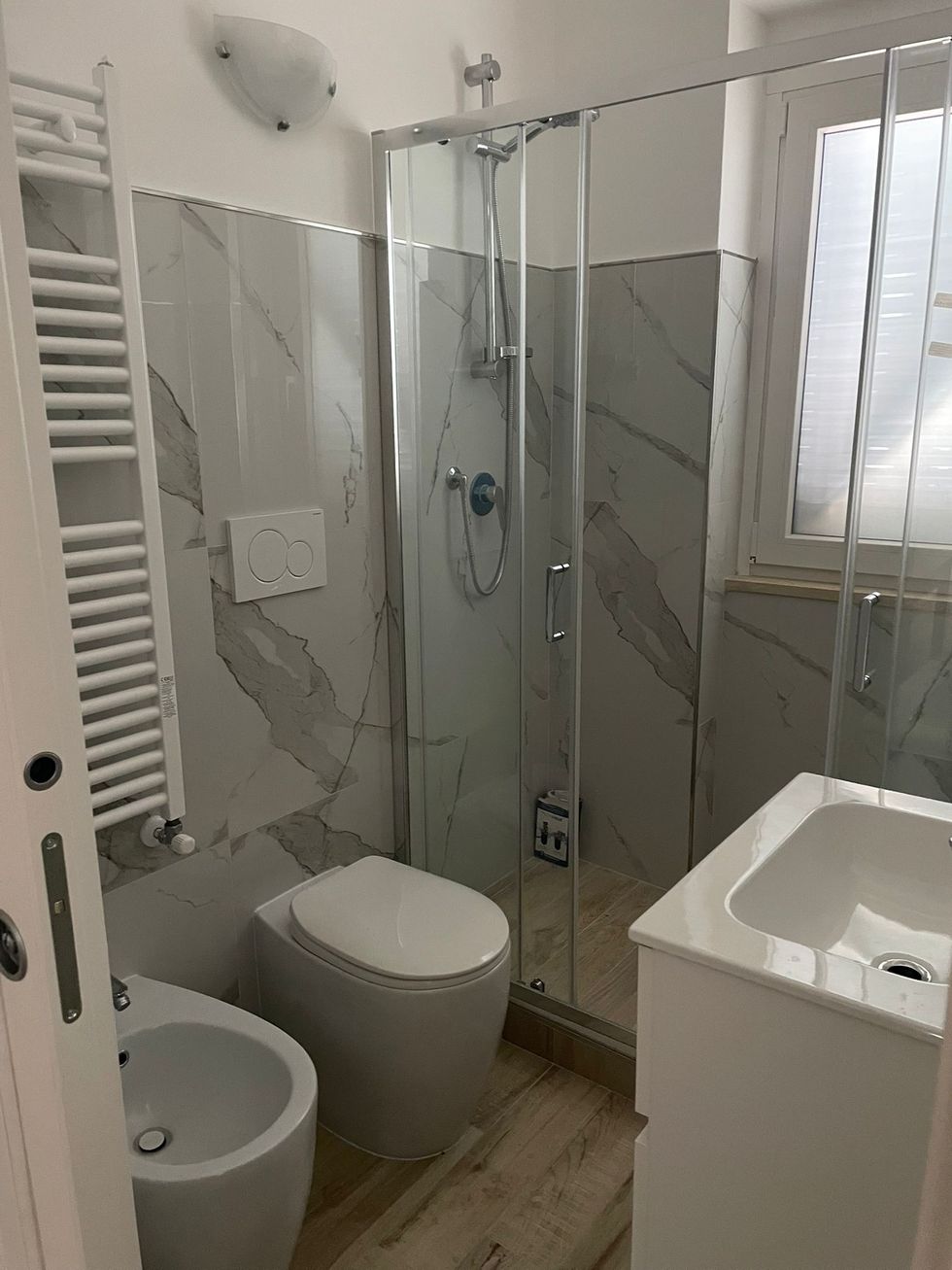 Un palazzo color beige in fase di ristrutturazione, completamente ricoperto da impalcature metalliche argentate, stagliarsi contro un cielo azzurro nuvoloso.