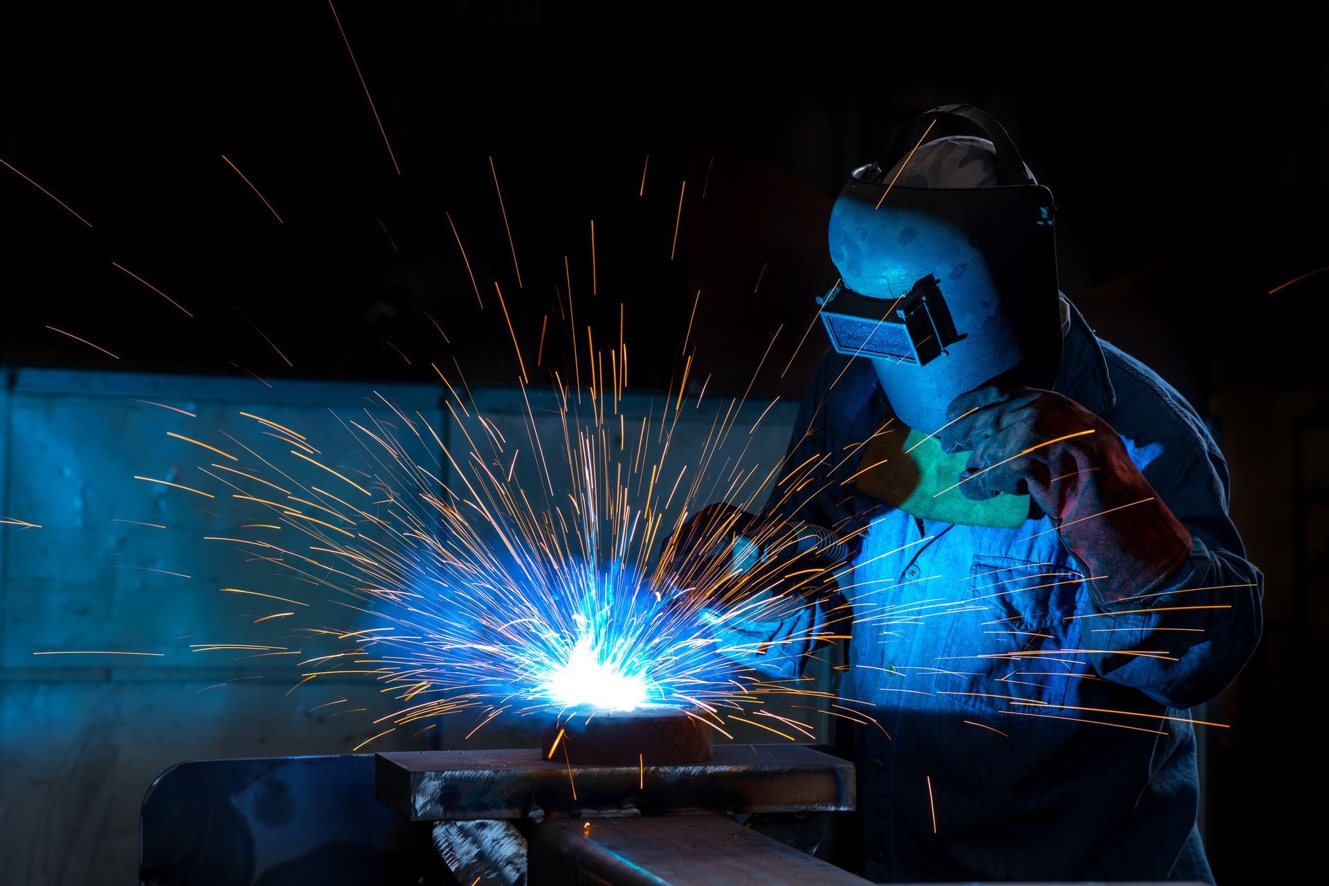 A welder works on metal as sparks fly, showcasing the skill of a steel fabricator in action. 