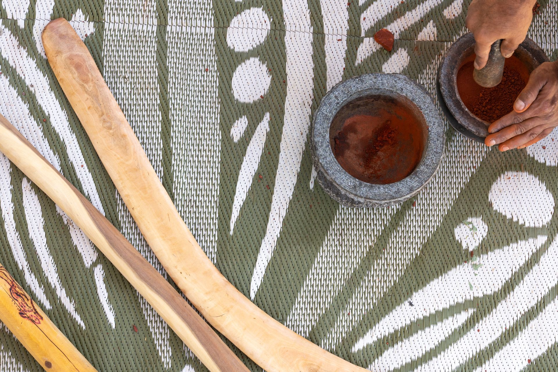 A person is holding a mortar and pestle over a bowl of liquid.