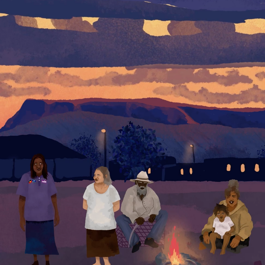 A group of people standing around a fire with mountains in the background