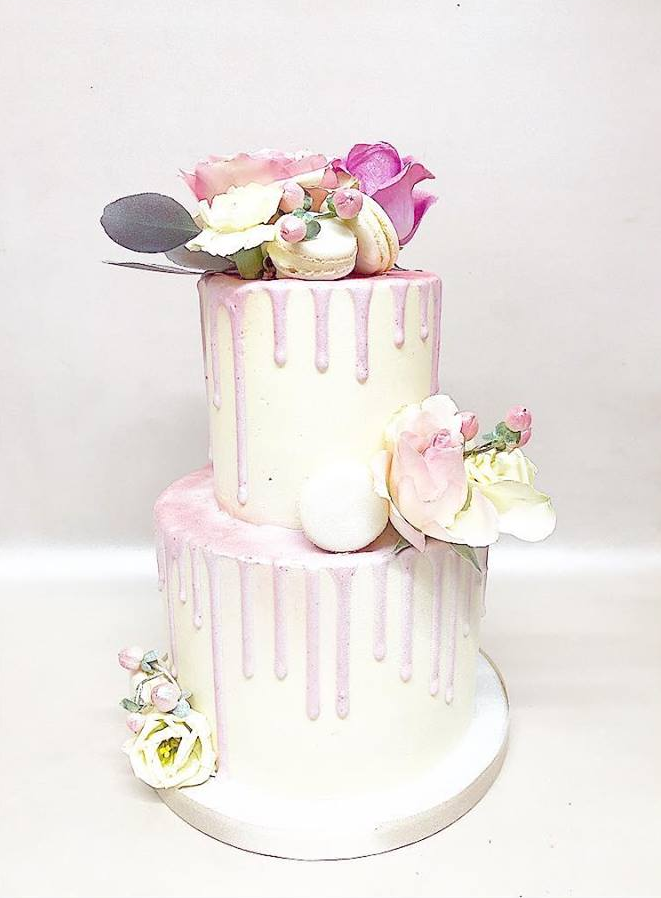 A white cake with pink frosting and flowers on top.