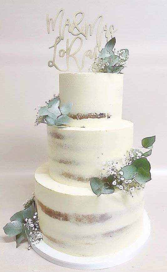 A three tiered wedding cake with a topper on top of it.
