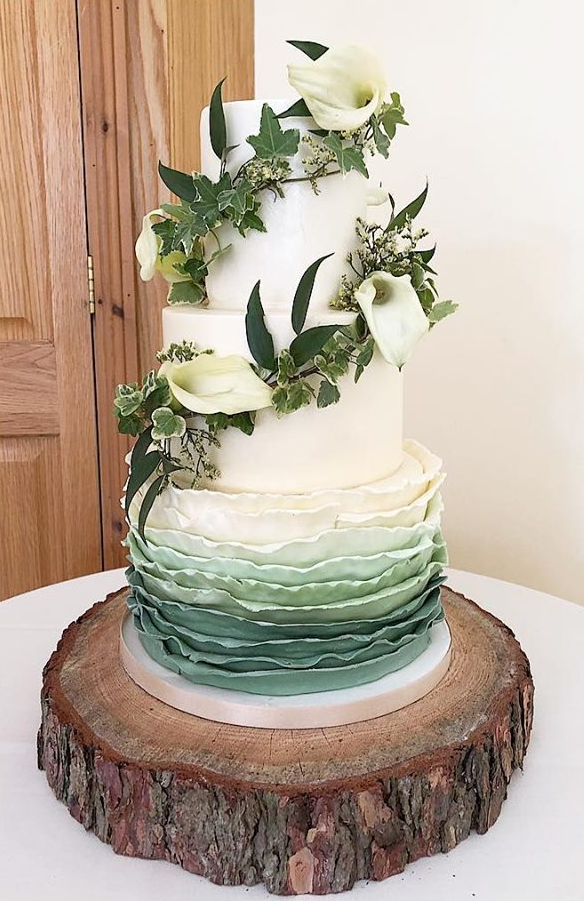 A wedding cake is sitting on top of a wooden stump.