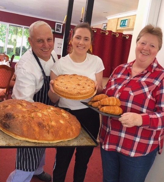 Gabriella and family  holding trays of food including a pie and croissants