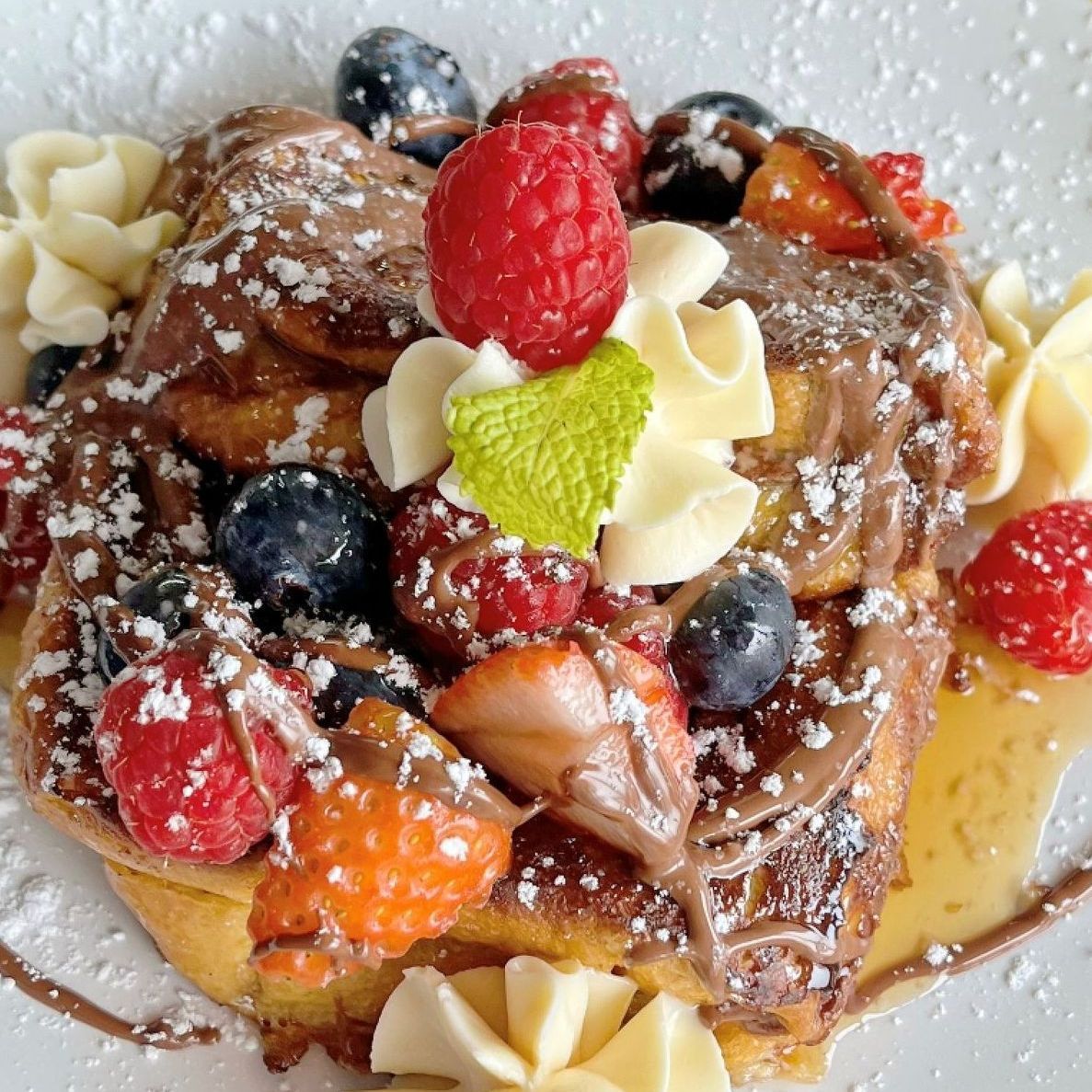 A close up of a dessert with berries and whipped cream on a plate.