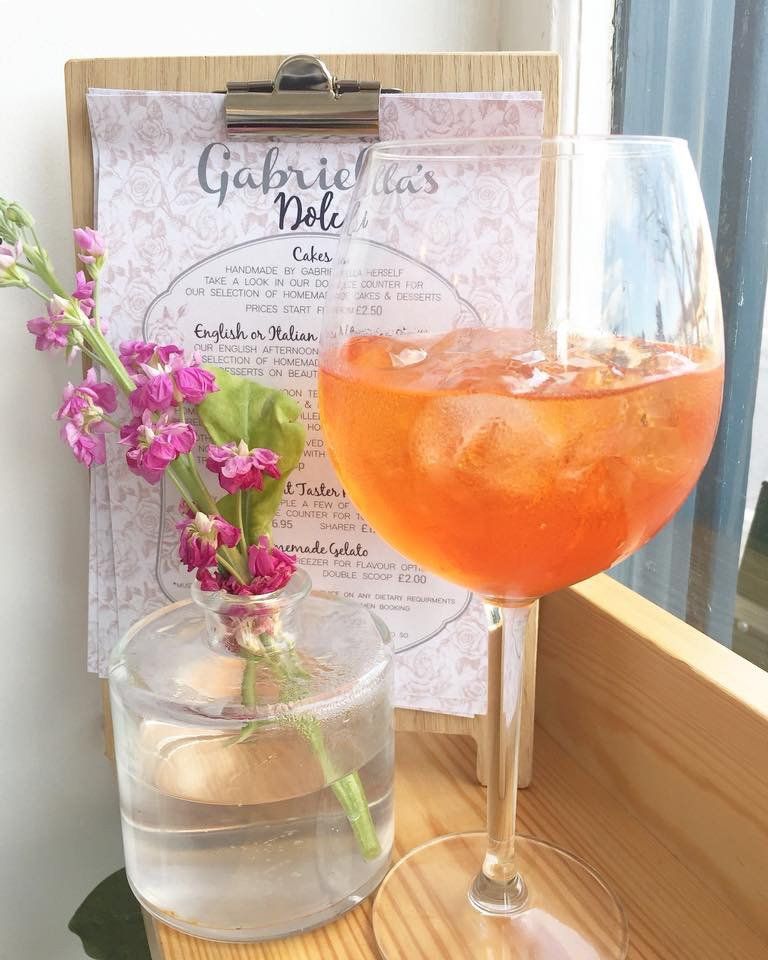 A glass of wine is sitting on a wooden table next to a vase of flowers.