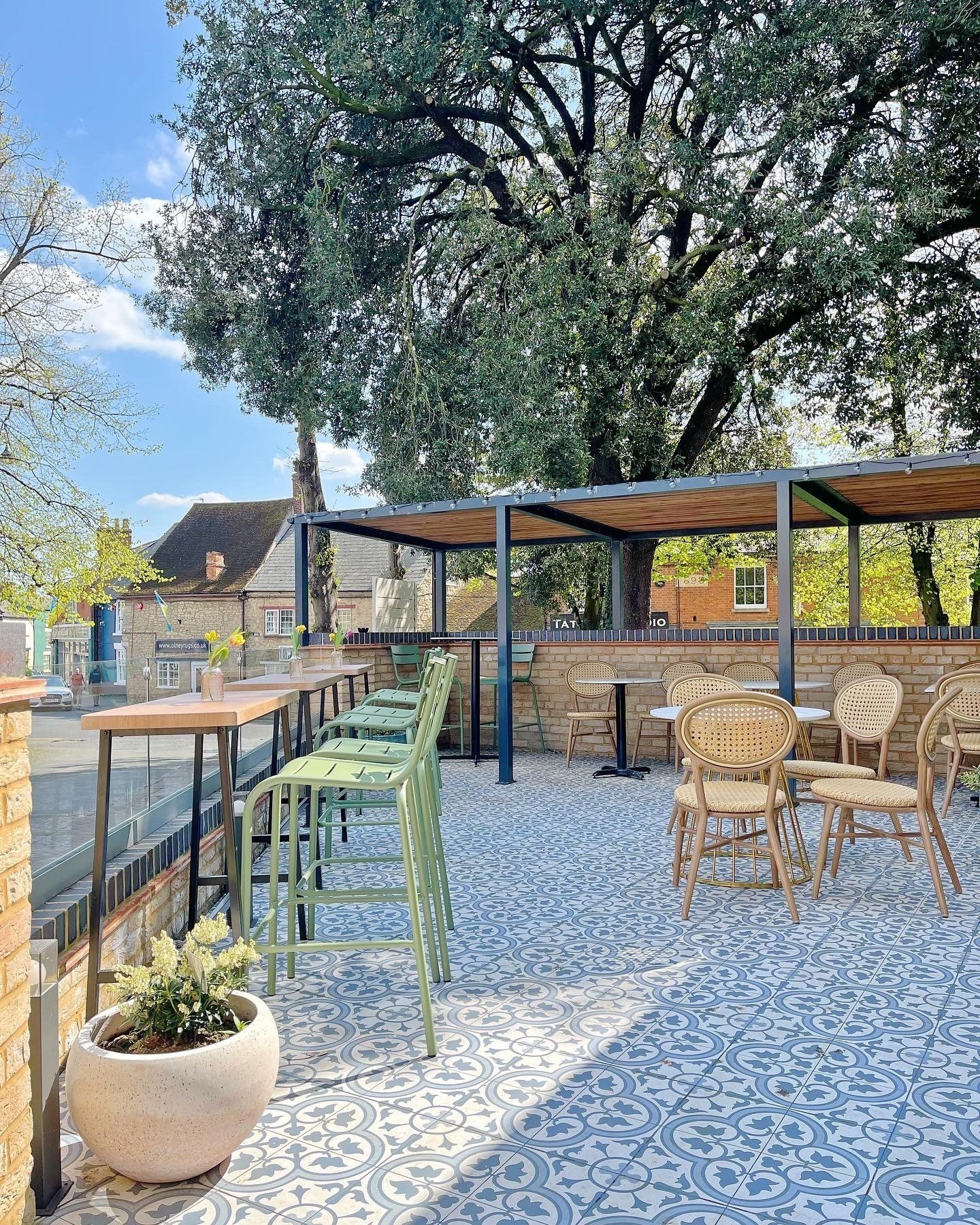 Locanda Gabriella patio with tables and chairs and a tree in the background.