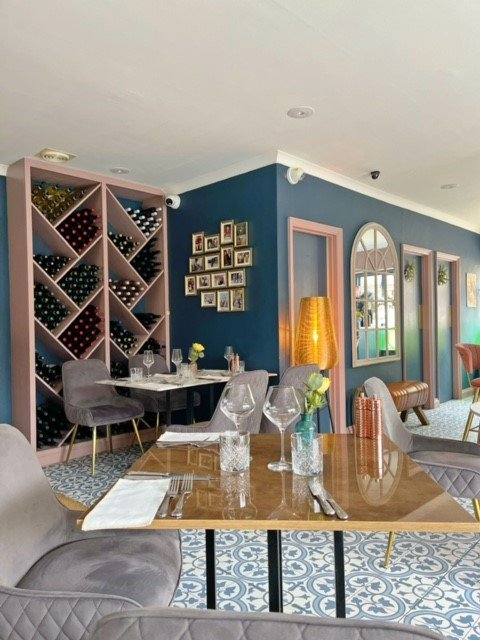 A restaurant with tables and chairs and a wine rack