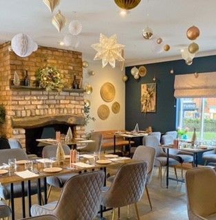 A restaurant with tables and chairs and decorations hanging from the ceiling.
