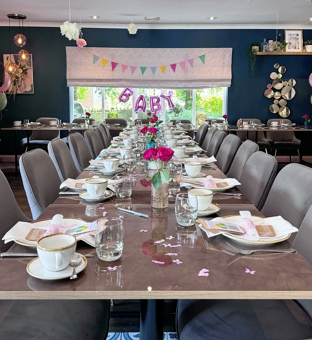 A long table set for a baby shower with plates and cups on it