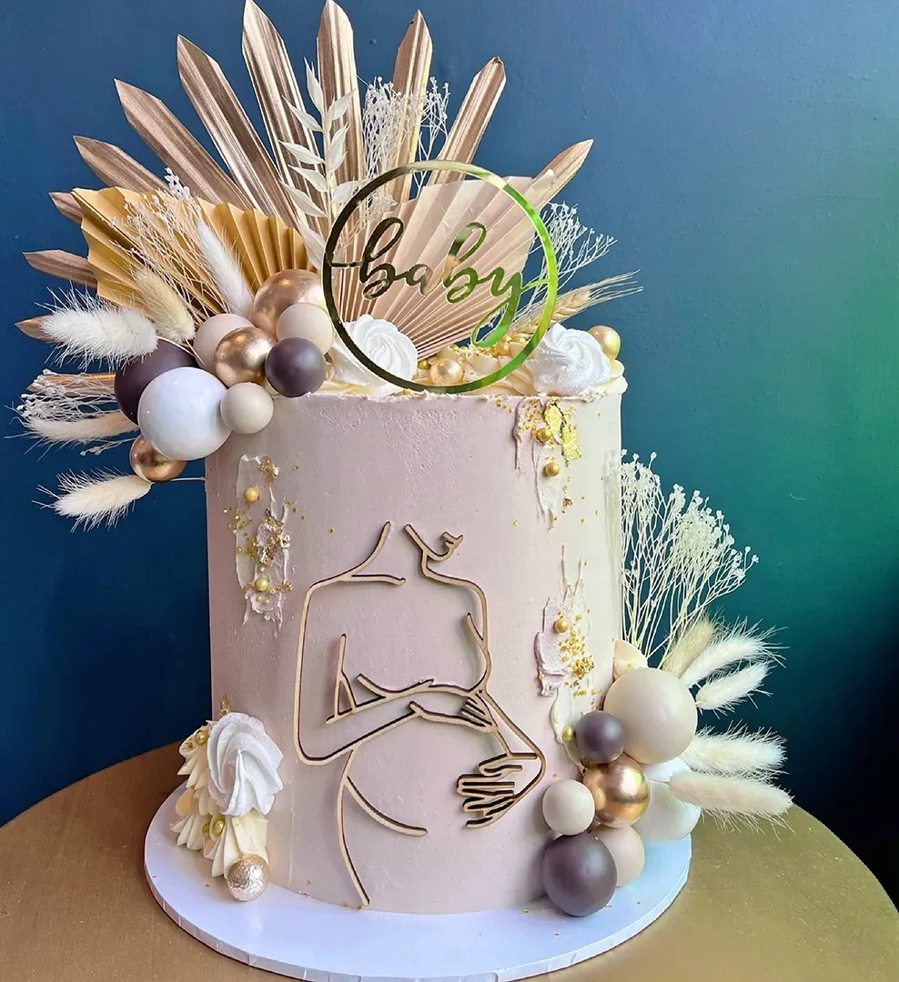 A cake with flowers and balloons on it is sitting on a table.