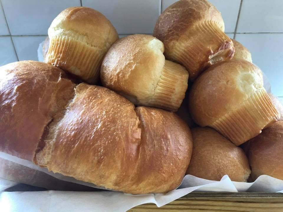 A basket filled with rolls and muffins on a table.