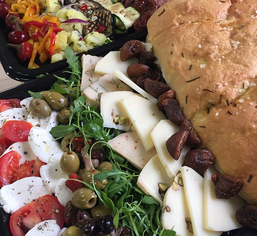 A close up of a plate of food with tomatoes olives and cheese
