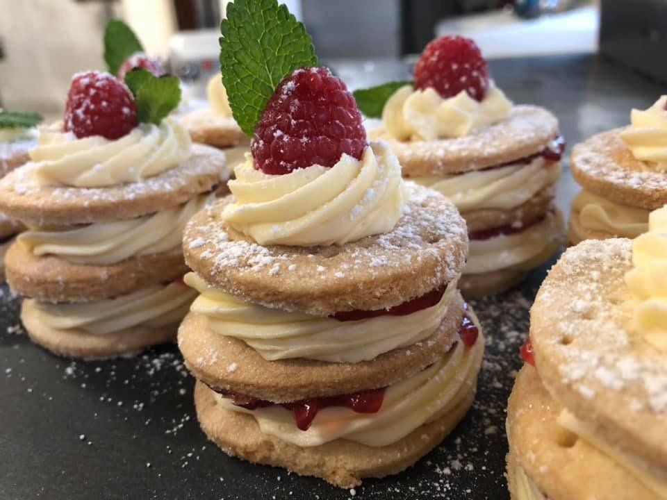 A stack of cookies with whipped cream and raspberries on top.