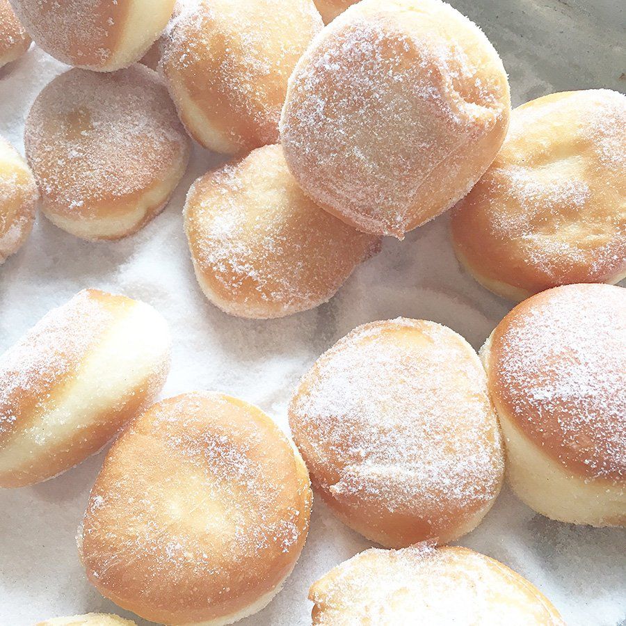 A bunch of doughnuts with powdered sugar on them