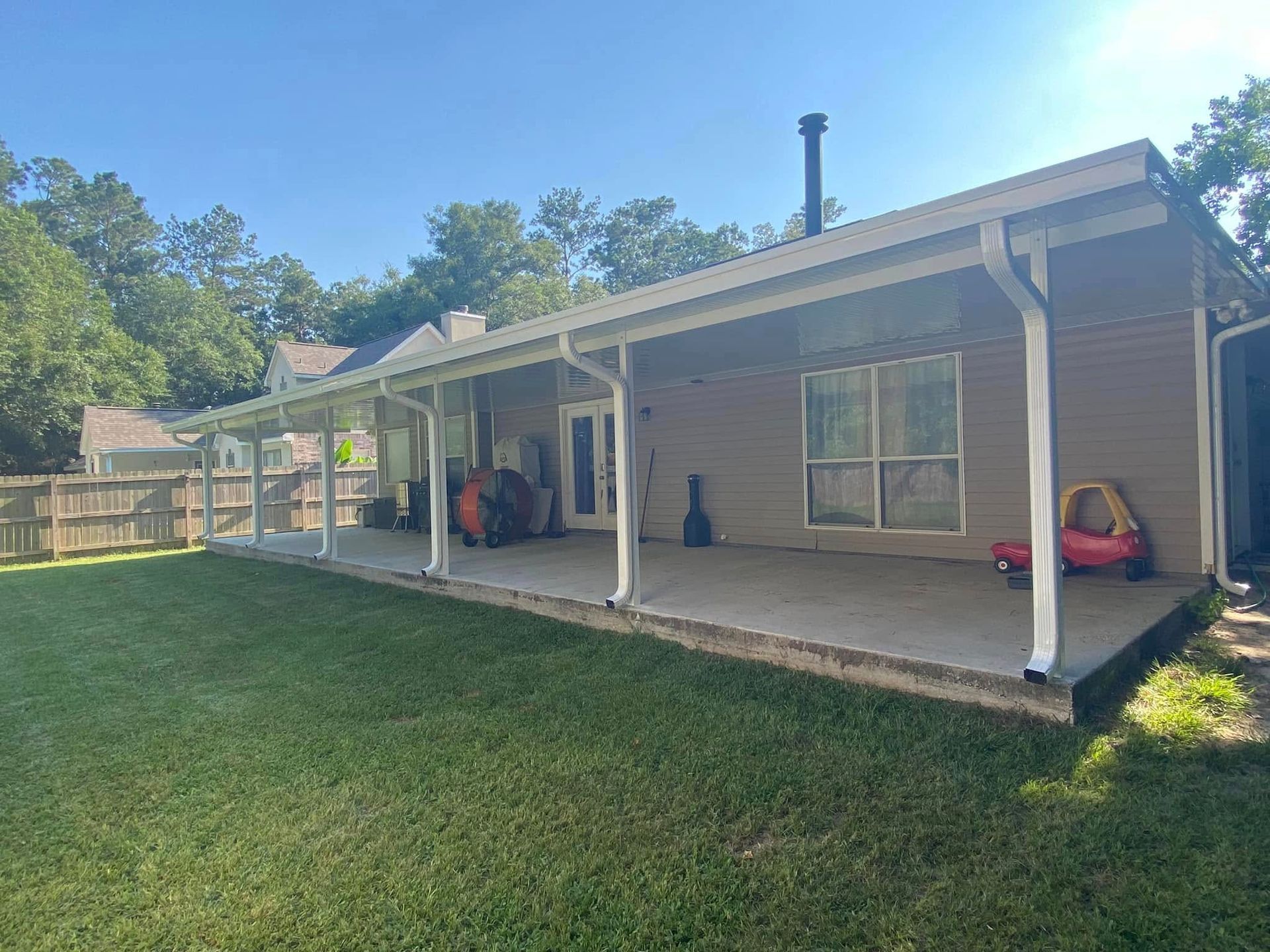 Backyard patio with a concrete floor, brown siding, and a green lawn.