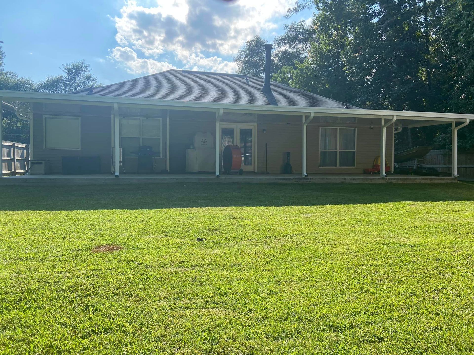 Tan house with white-framed porch, green grass, and blue sky.