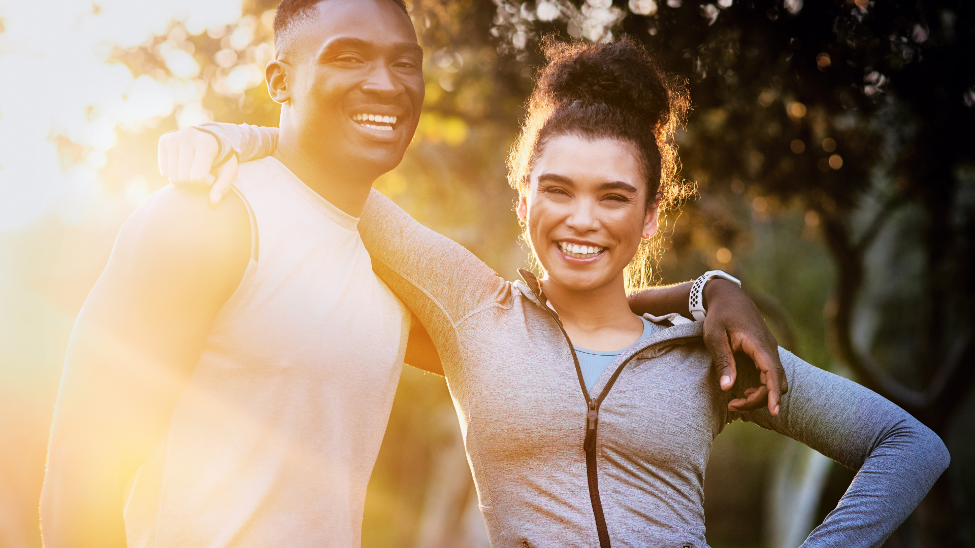 A man and a woman are posing for a picture in a park.