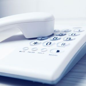 White landline telephone with receiver off the hook, resting on keypad.