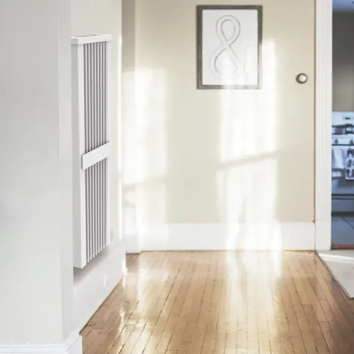 White wall-mounted air purifier in hallway with wood floor. Sunlight streams in.