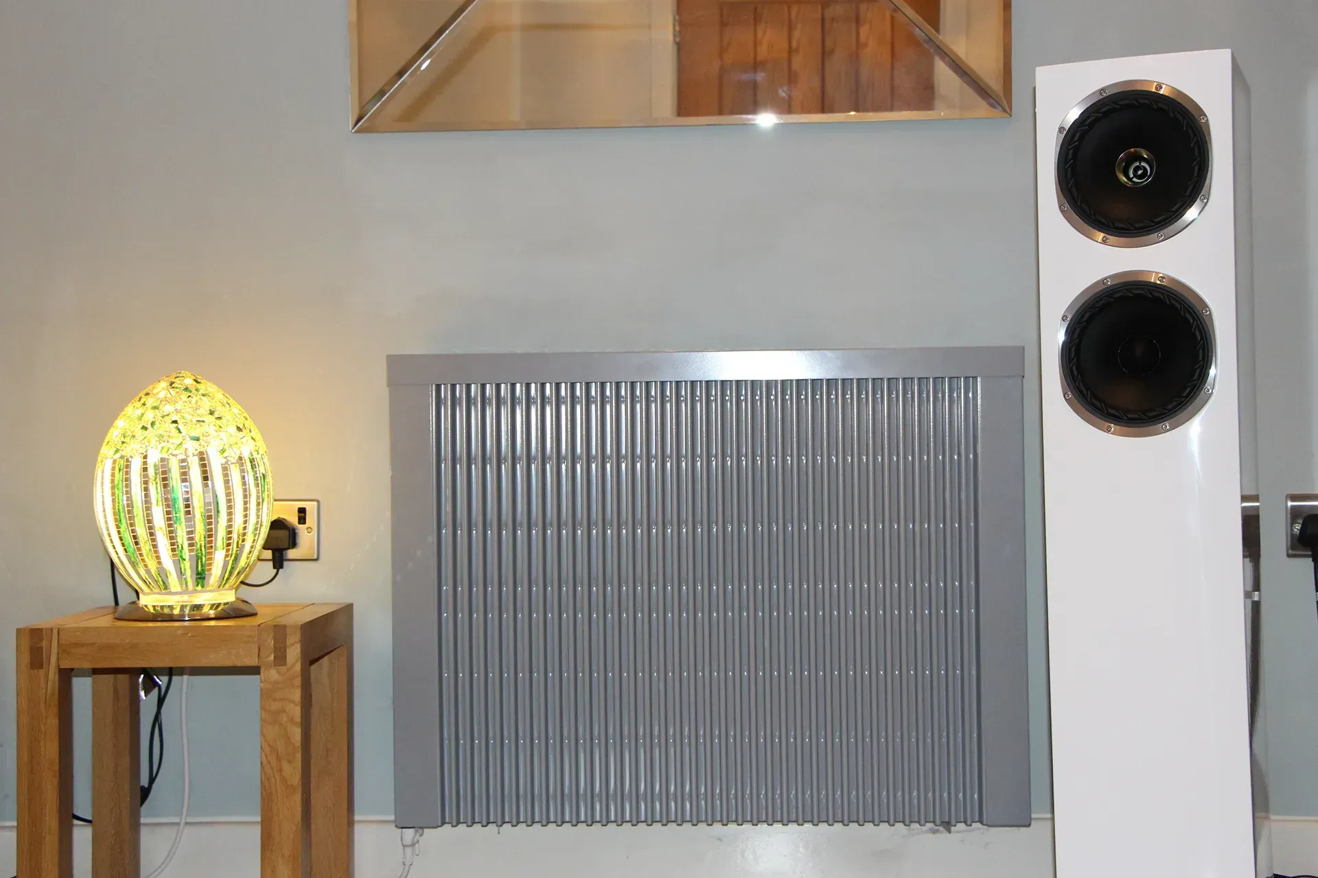 White wall heater on a burnt orange wall, next to a sofa and plant.