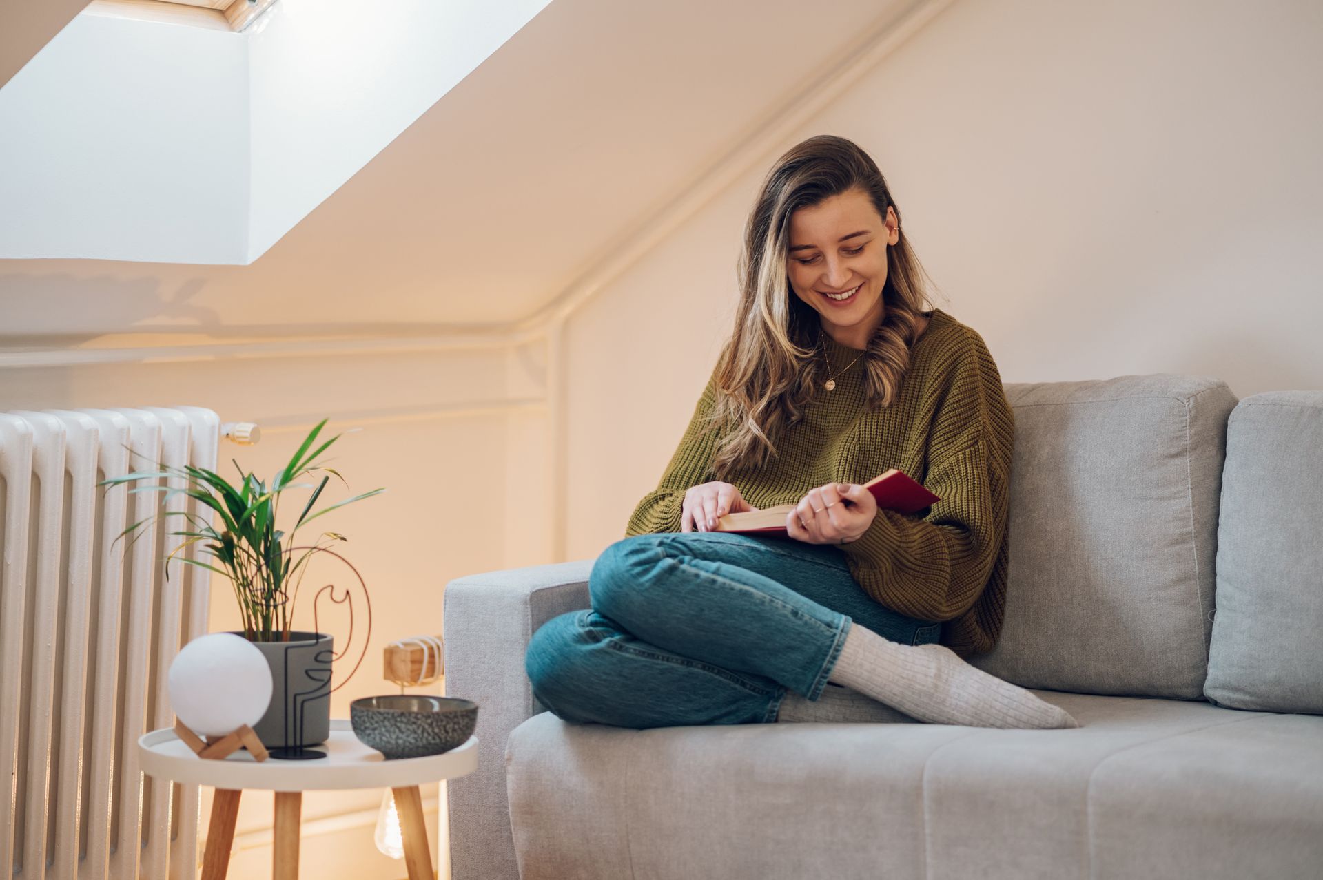 A woman is sitting on a couch looking at her phone.