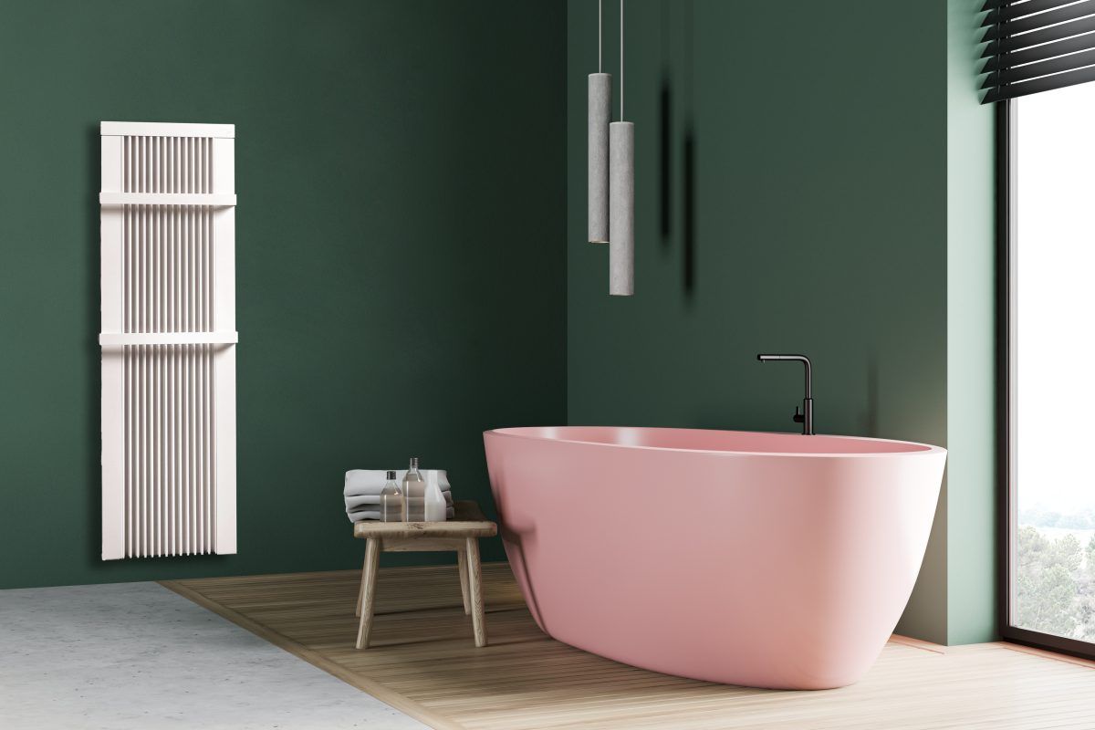 A bathroom with green walls and a pink bathtub.