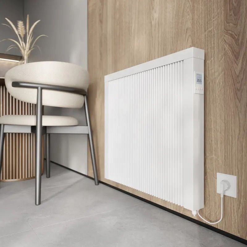 A white radiator is plugged into a wall next to a chair