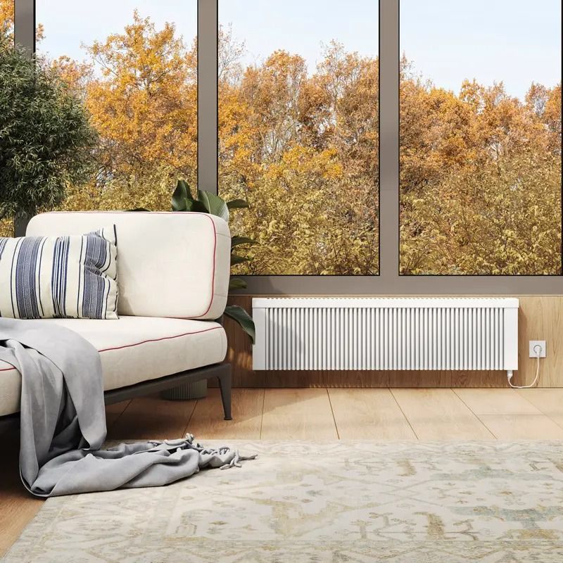 A living room with a couch and a radiator in front of a window.