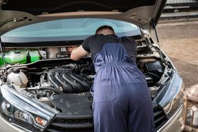 Mechanic Working Under Vehicle Hood | Knost Tire & Automotive