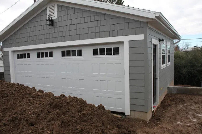Renovate208.com: A gray garage with a white door is sitting on top of a pile of dirt.