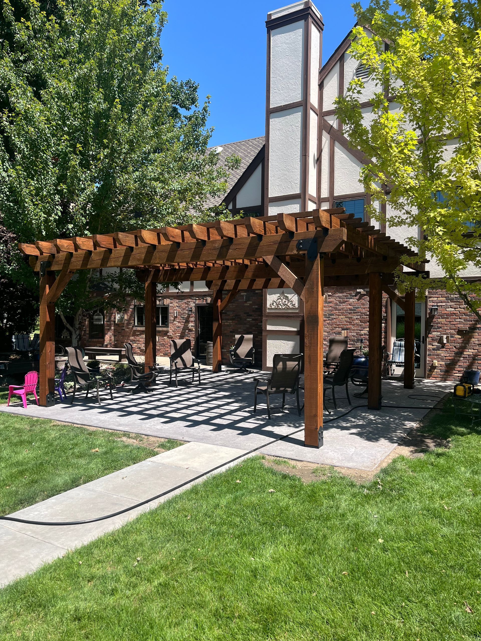 Renovate208.com: There is a wooden pergola in the backyard of a house.