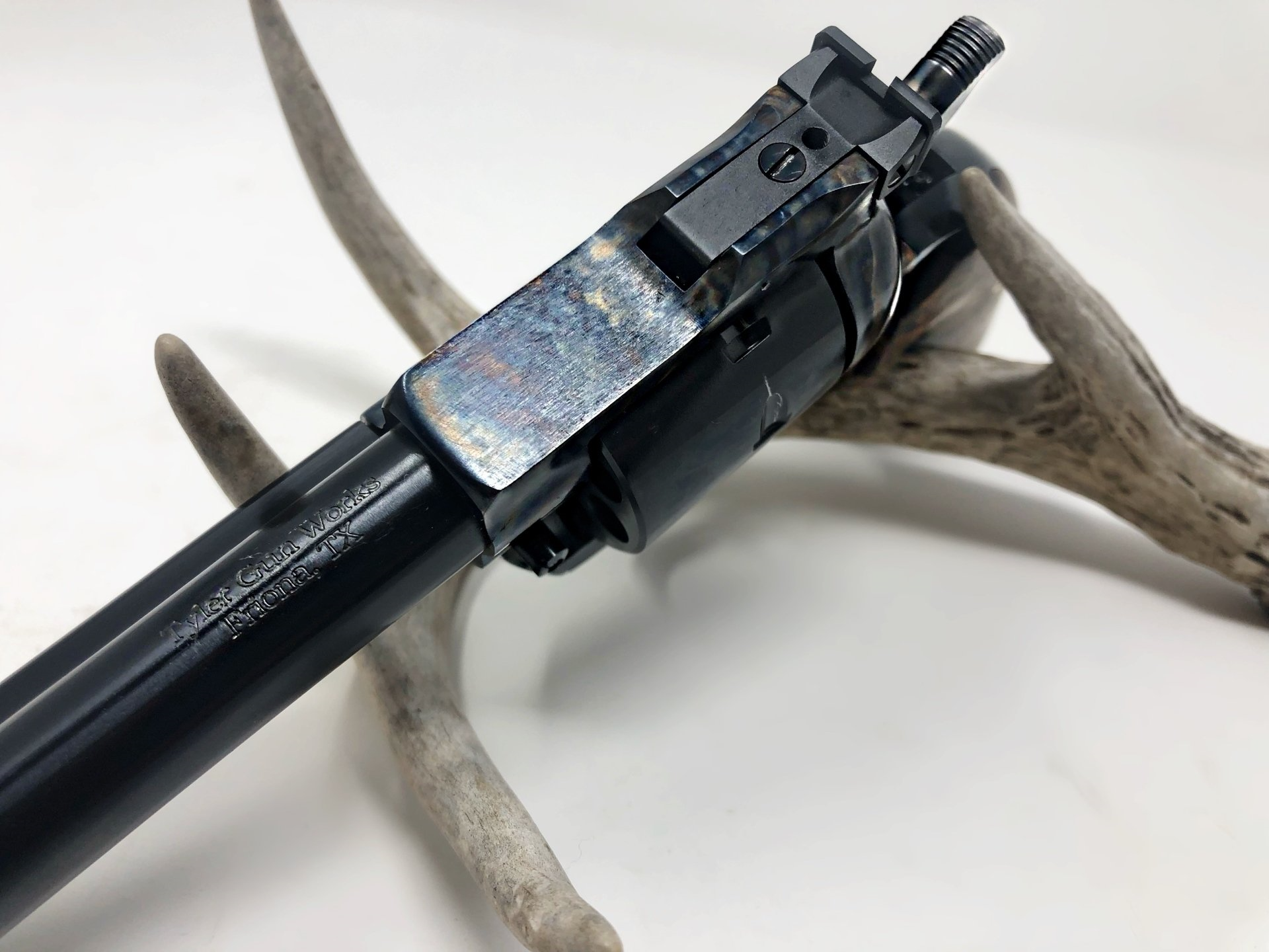 Black rifle barrel with visible front sight, resting on antlers.